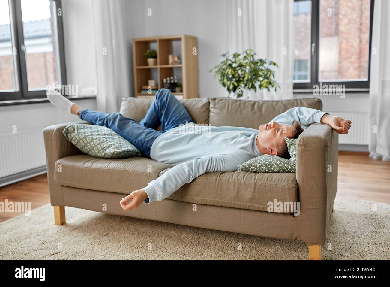 bored or lazy young man lying on sofa at home Stock Photo
