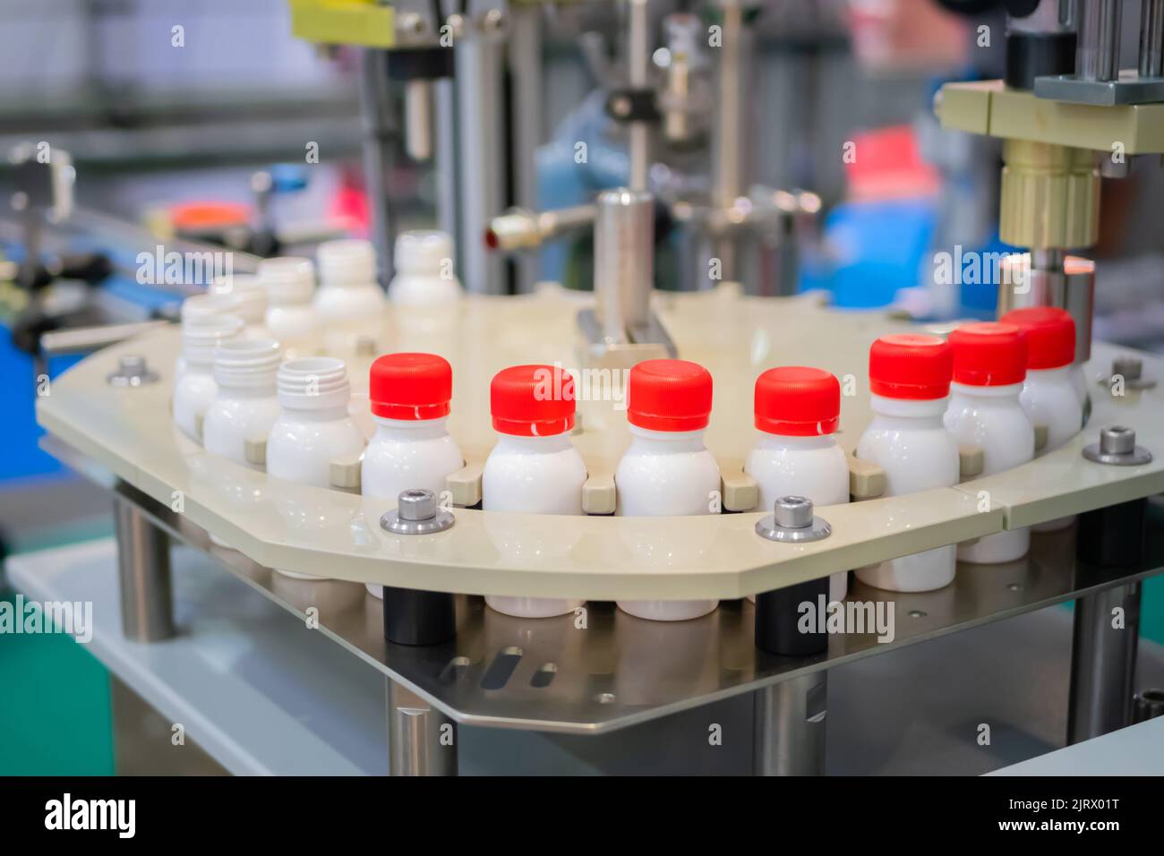 Row of white pet bottles with dairy product on conveyor belt close up