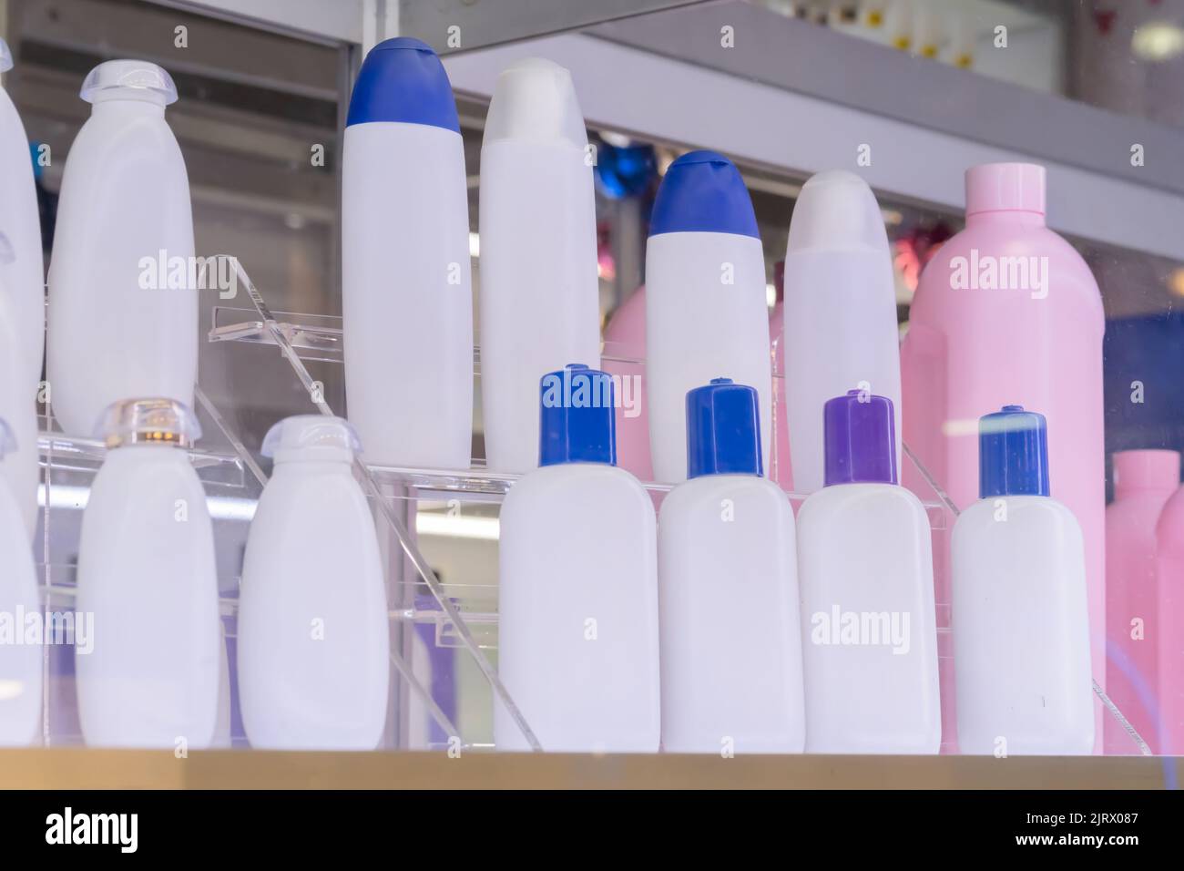Empty white and pink plastic shampoo or shower gel bottles in showcase