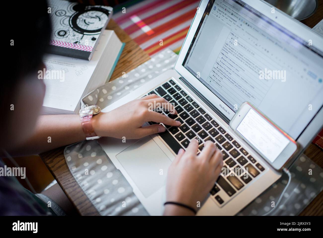 Student with a laptop computer doing her homework using multiple ...