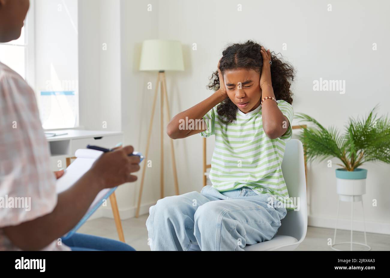 Teenage girl with negative mood shows that she does not want to listen to psychologist. Stock Photo