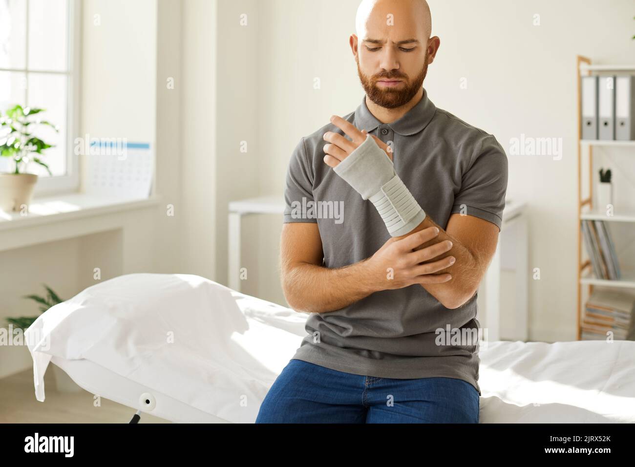 Injured man was put on medical bandage for his wrist at hospital after receiving arm injury. Stock Photo