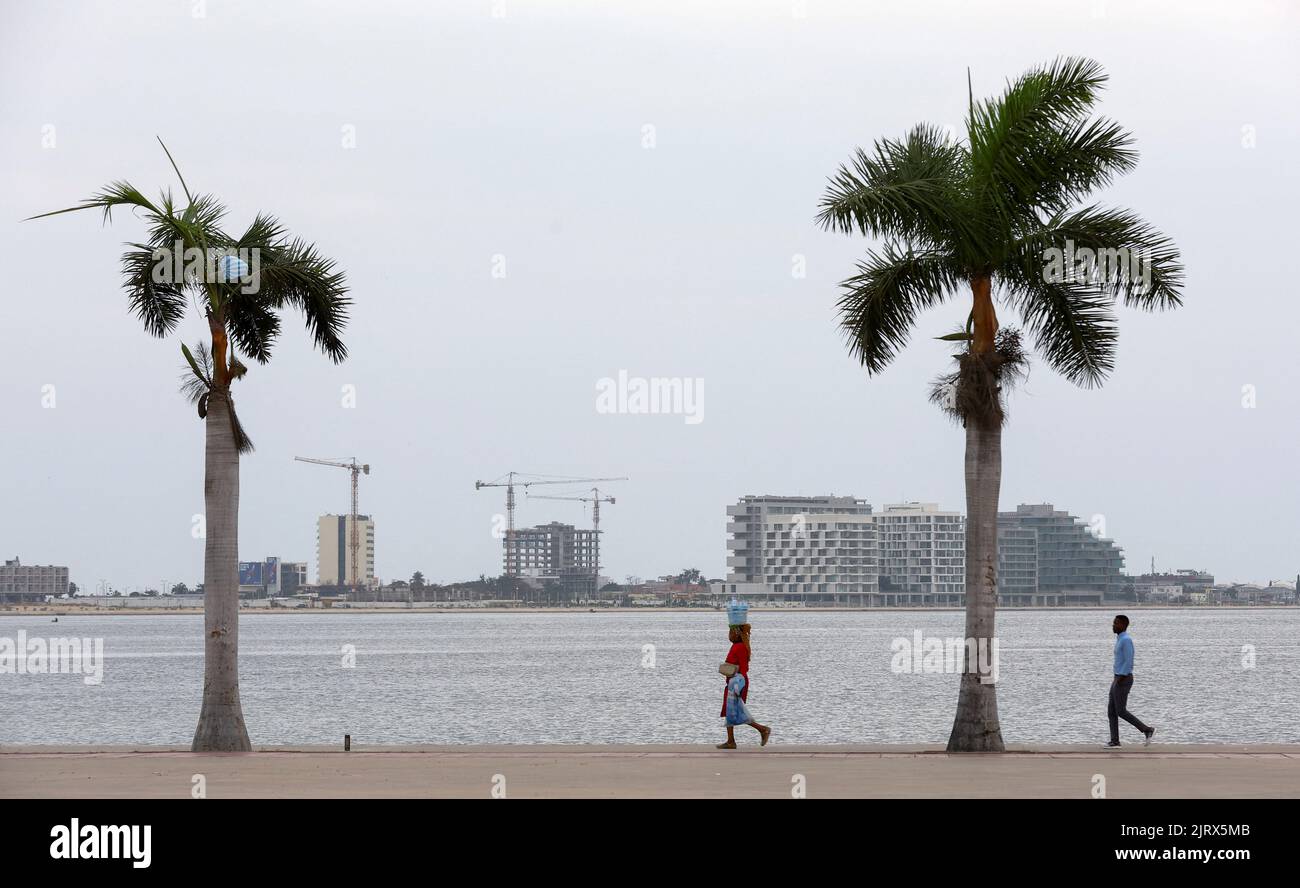 People walk as office buildings under construction are seen in the distance, in Luanda, Angola, August 26, 2022. REUTERS/Siphiwe Sibeko Stock Photo