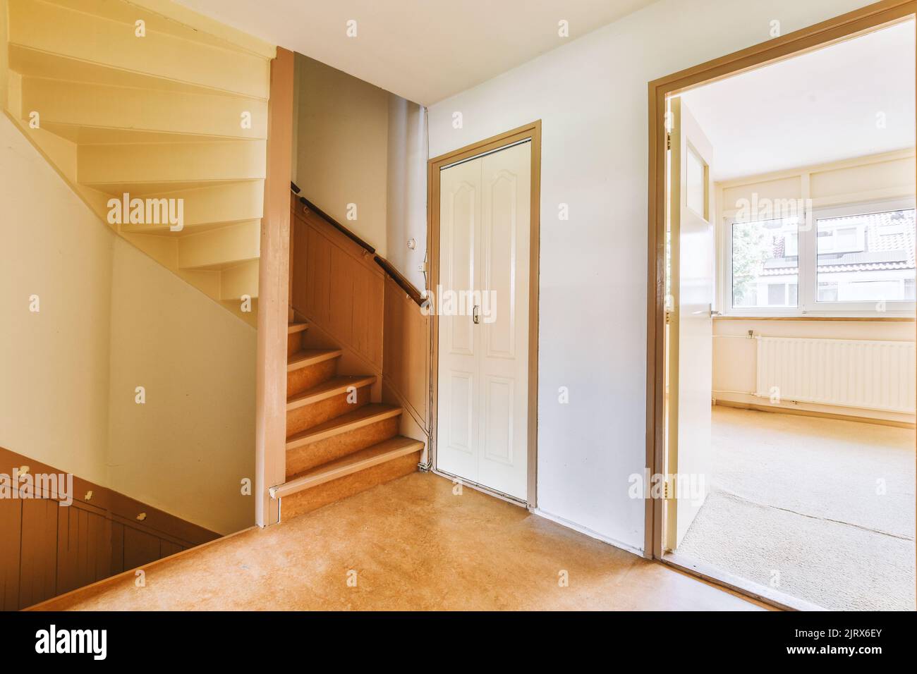 White hallway with wooden stairway leading to second floor of modern ...