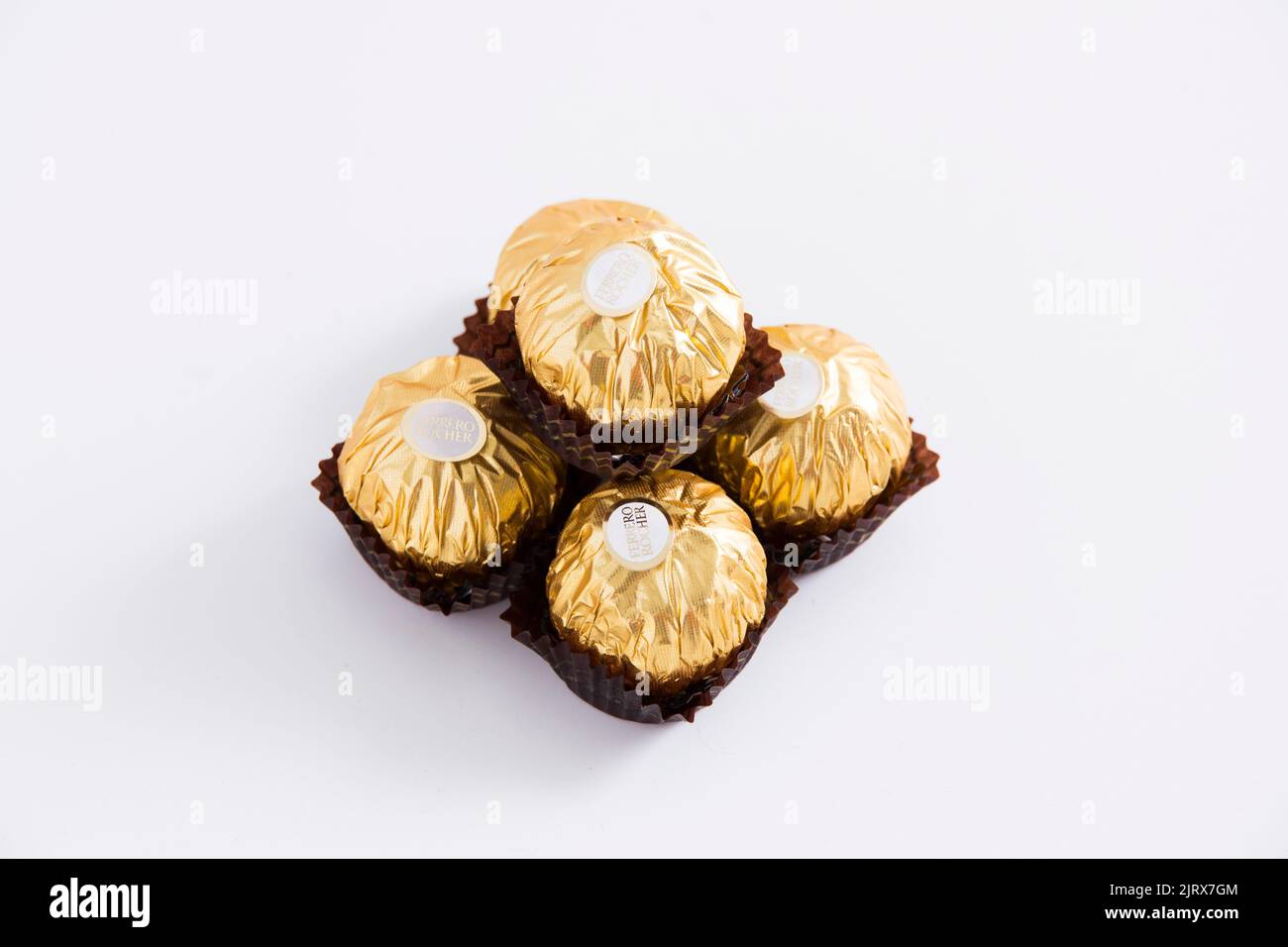 A closeup of stacked chocolate gold bonbons of Ferrero Rocher on a white table Stock Photo