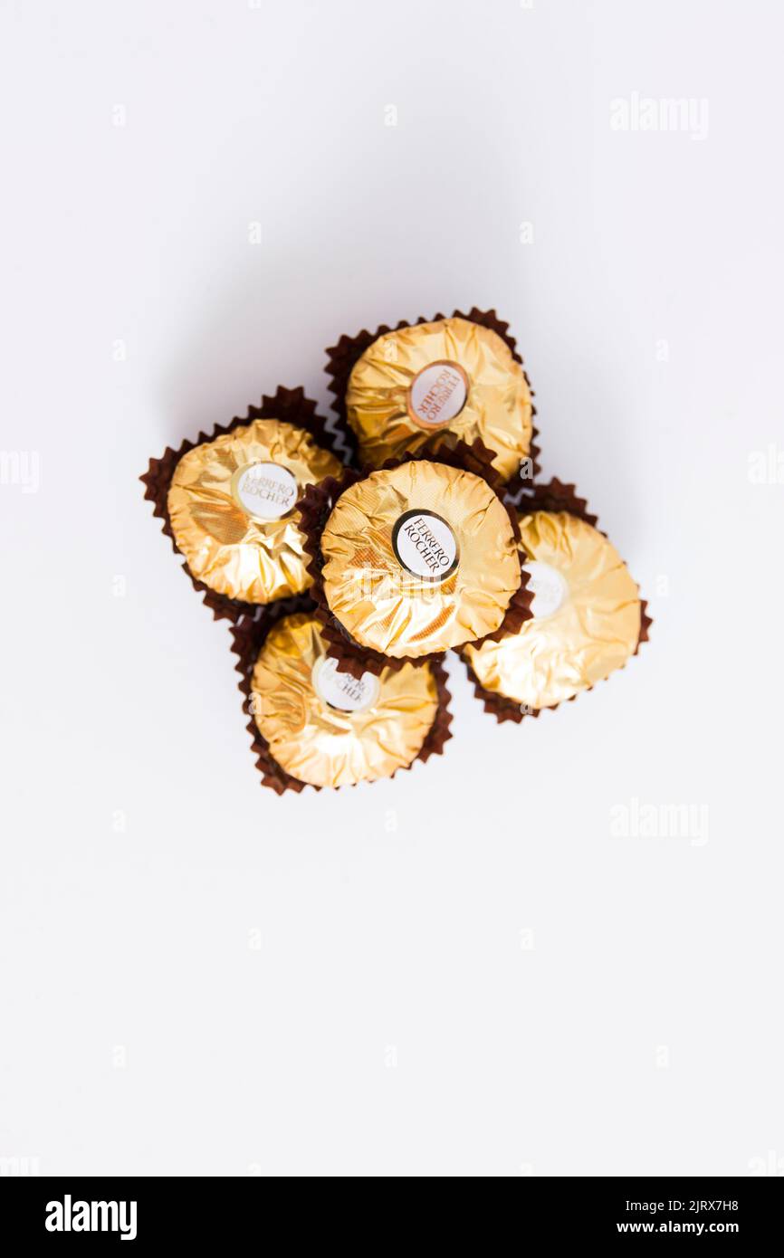 A closeup of a bunch of chocolate gold bonbons of Ferrero Rocher on a white table Stock Photo