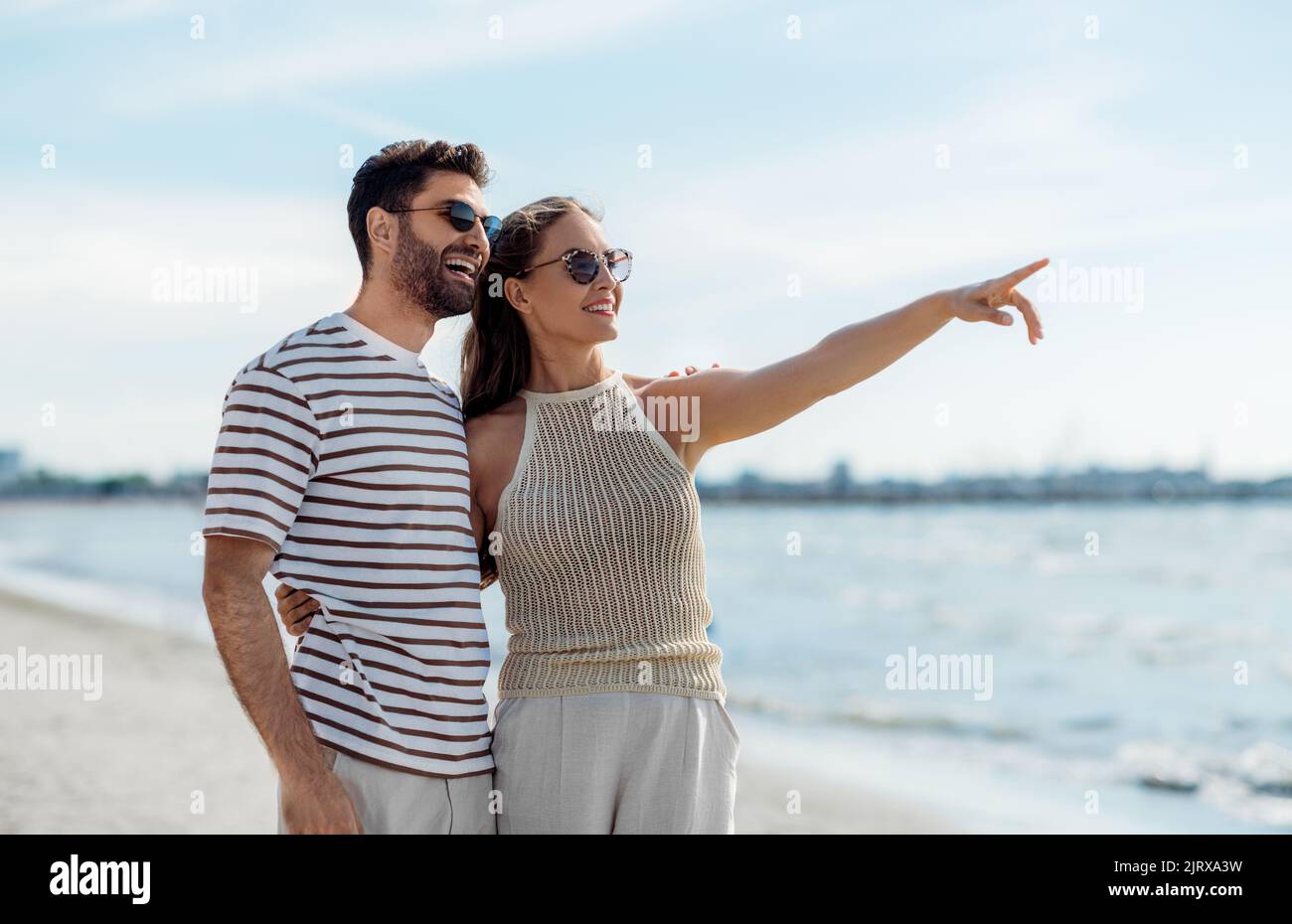 happy couple pointing finger on summer beach Stock Photo - Alamy