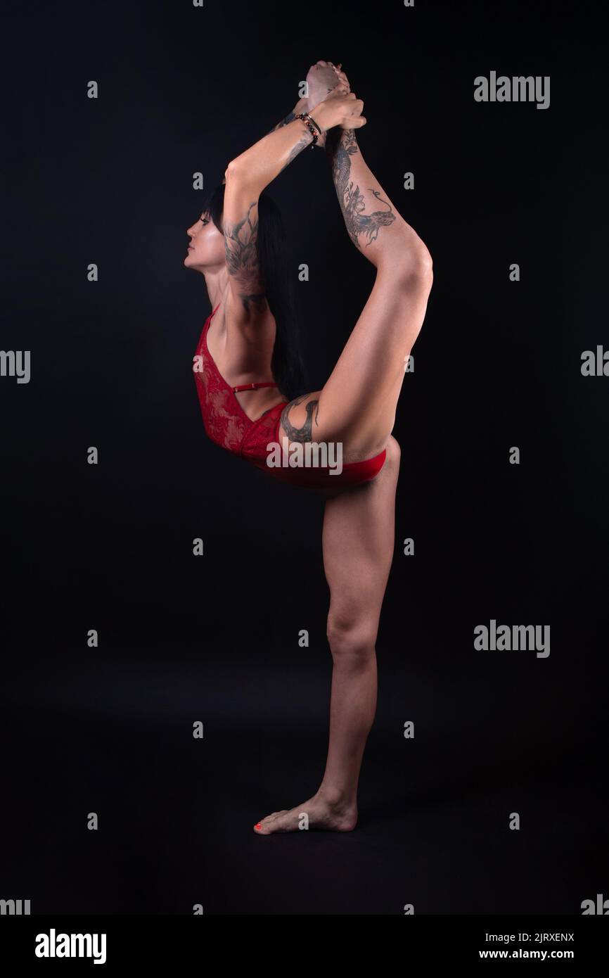 Photo of gymnast girl with tattoo stretching in red lingerie Stock Photo