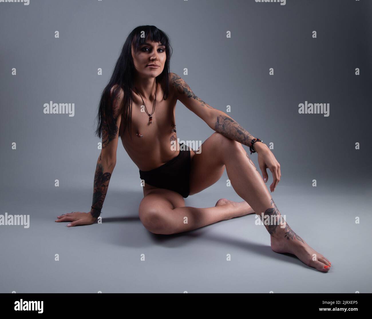 Photo of the topless woman in the panties sitting on the floor Stock Photo
