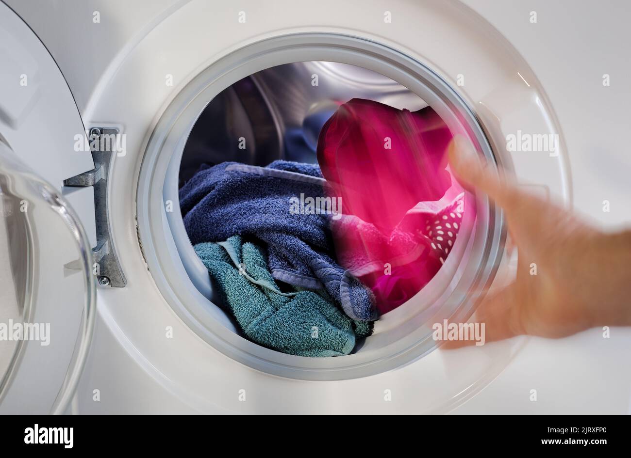 Filling coloureds clothes laundry in the washing machine, charging launder clothing items in the laundering washer Stock Photo