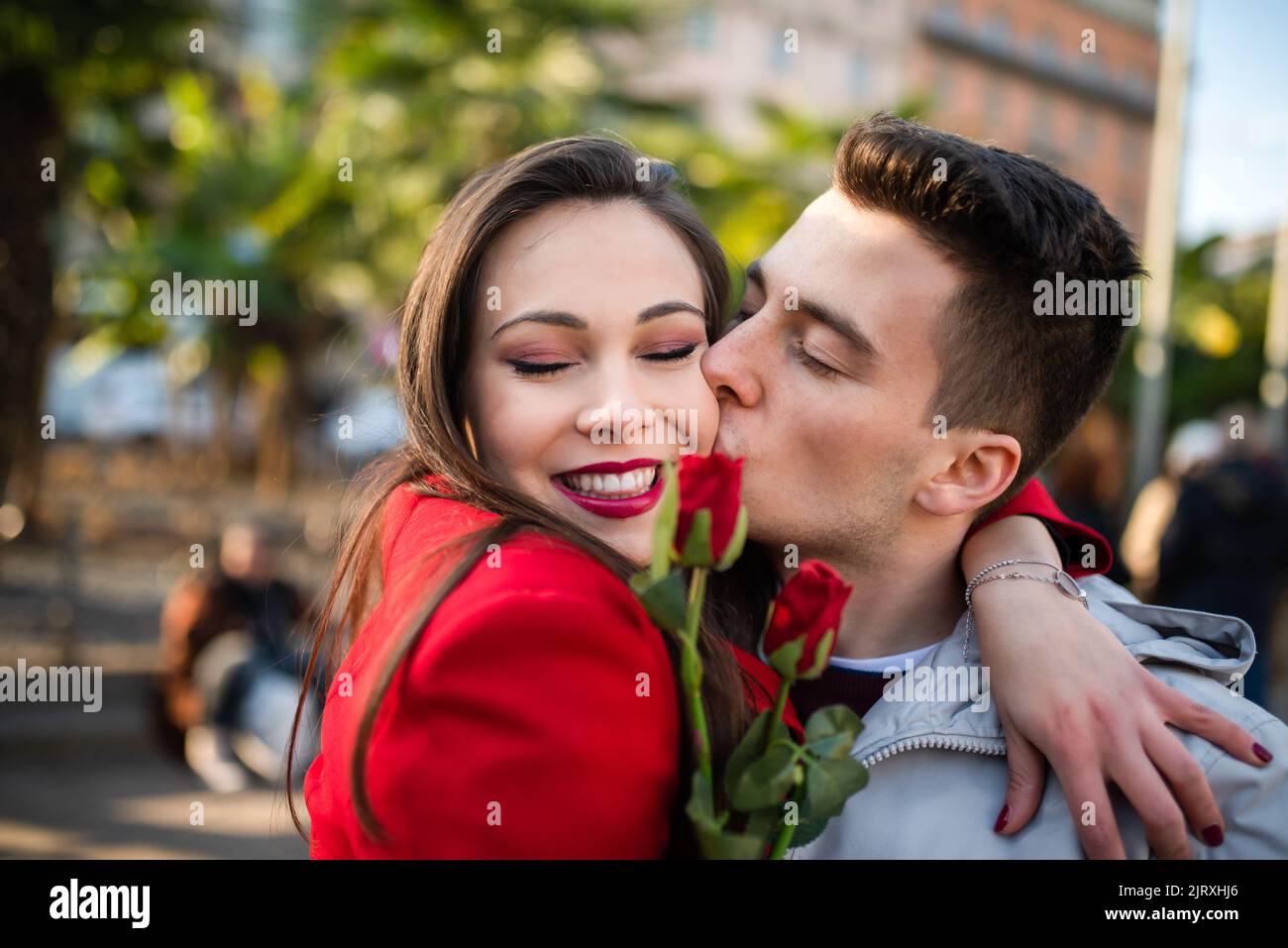 Young man giving flowers and kissing his girlfriend Stock Photo Alamy