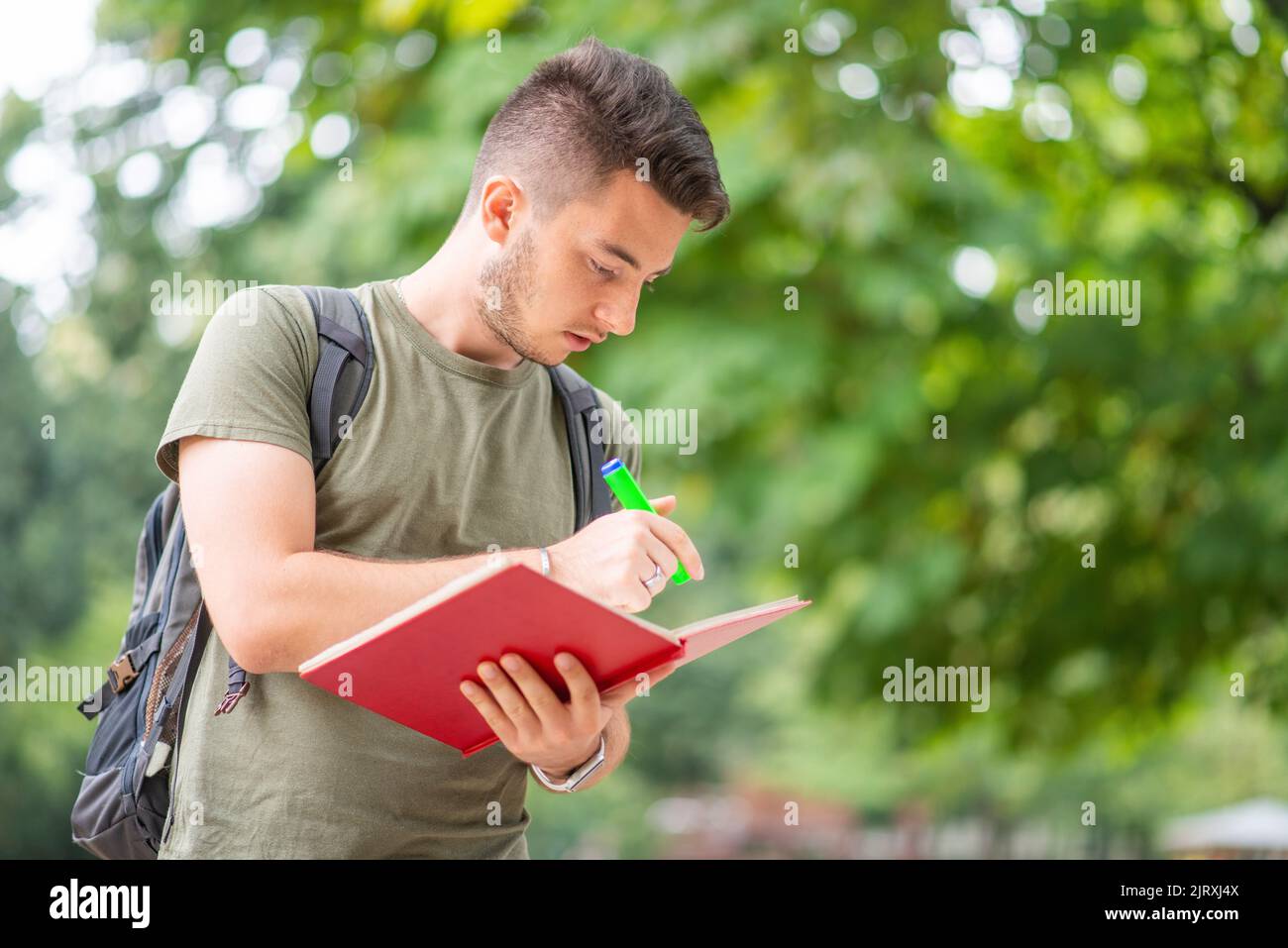 Student walking in a college park while studying a book Stock Photo - Alamy