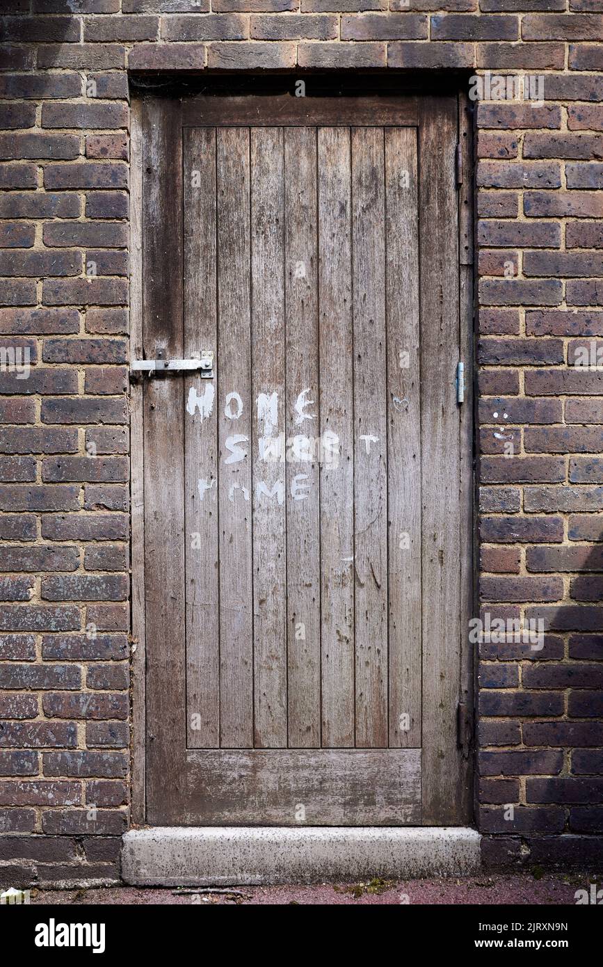 "Home, Sweet Home" written on worn wooden door Stock Photo