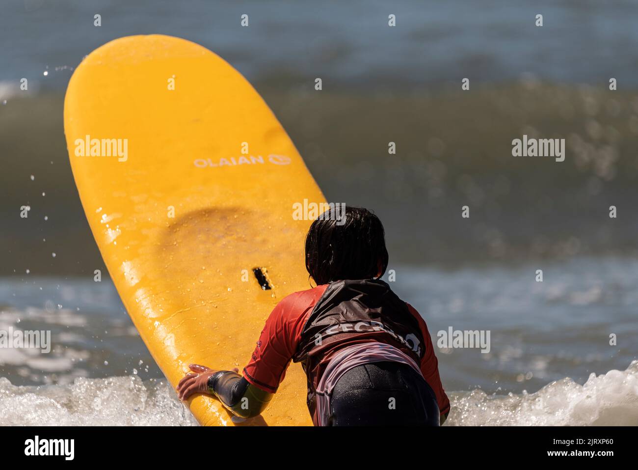 Aveiro, Portugal. august 19 - 2022: Surf lessons for children first class in the beach with yellow surfboard in the sea. Stock Photo