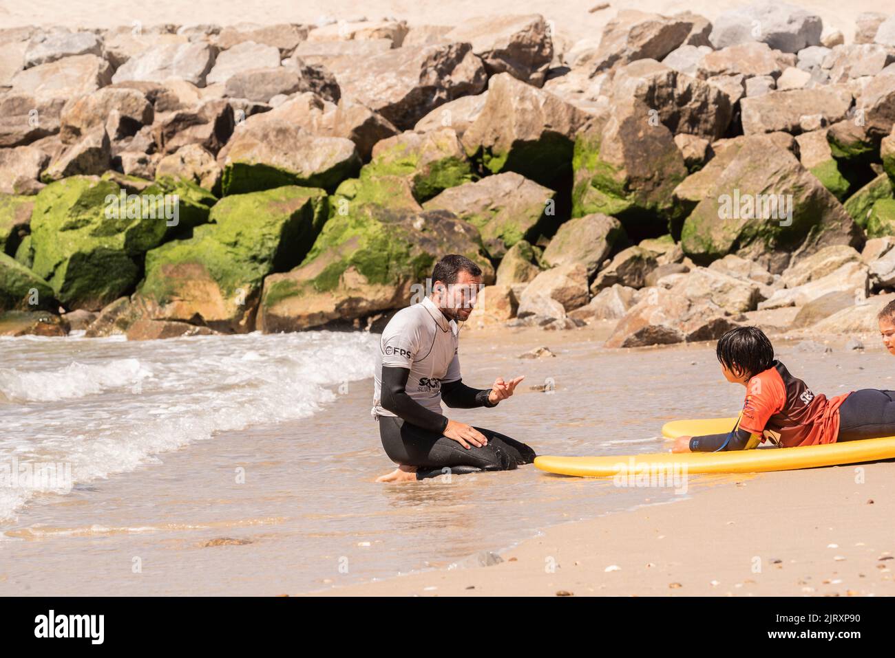 Aveiro, Portugal. august 19 - 2022: Surf lessons for children in the beach with surfboard in the sand. Stock Photo