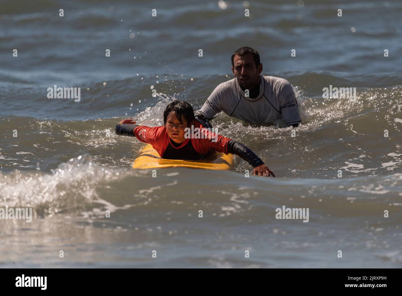 Aveiro, Portugal. august 19 - 2022: Surf lessons for children first class in the beach Take the first wave. Stock Photo