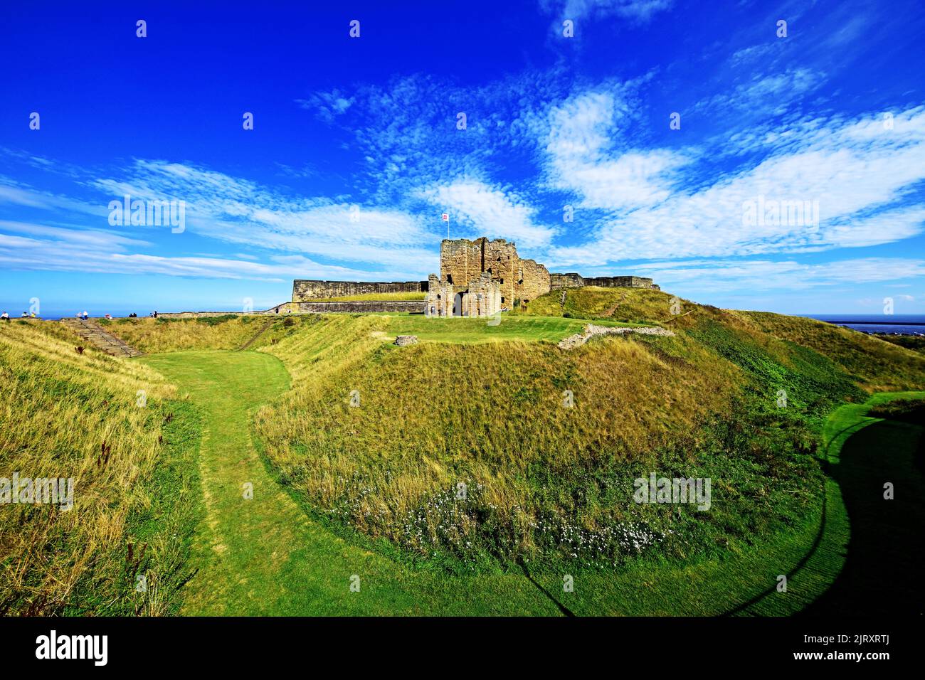 Tynemouth Castle and Priory also known as Pen Bal Crag with some visitors and a deep blue sky Stock Photo