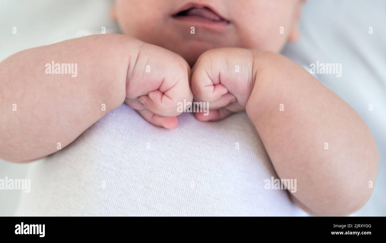 Close up of newborn boy hand on white sheet background. Baby sleeping on the bed. A beautiful conceptual image of childhood. Family and home concept Stock Photo