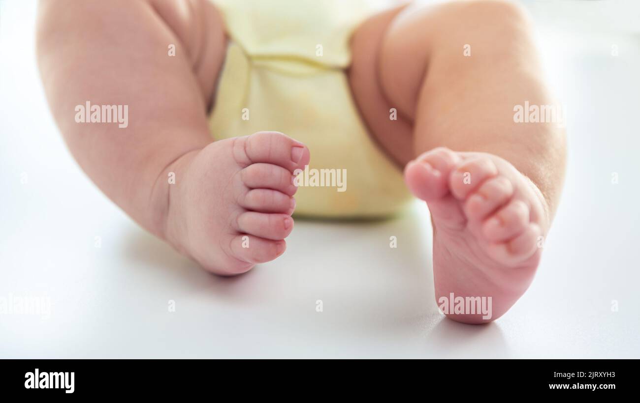 Baby foots on white sheet bed. Closeup of baby sleeping on the mother's room. Family and home concept Stock Photo