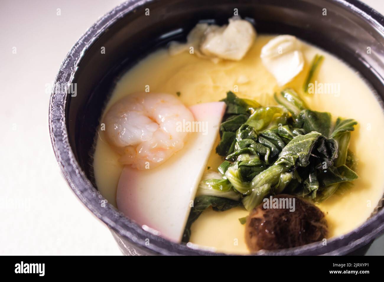 Closeup instant Chawanmushi. Chawanmushi is a Japanese savoury egg custard dish containing ginkgo seeds, kamaboko, Shiitake, spinach, chicken, etc. Stock Photo