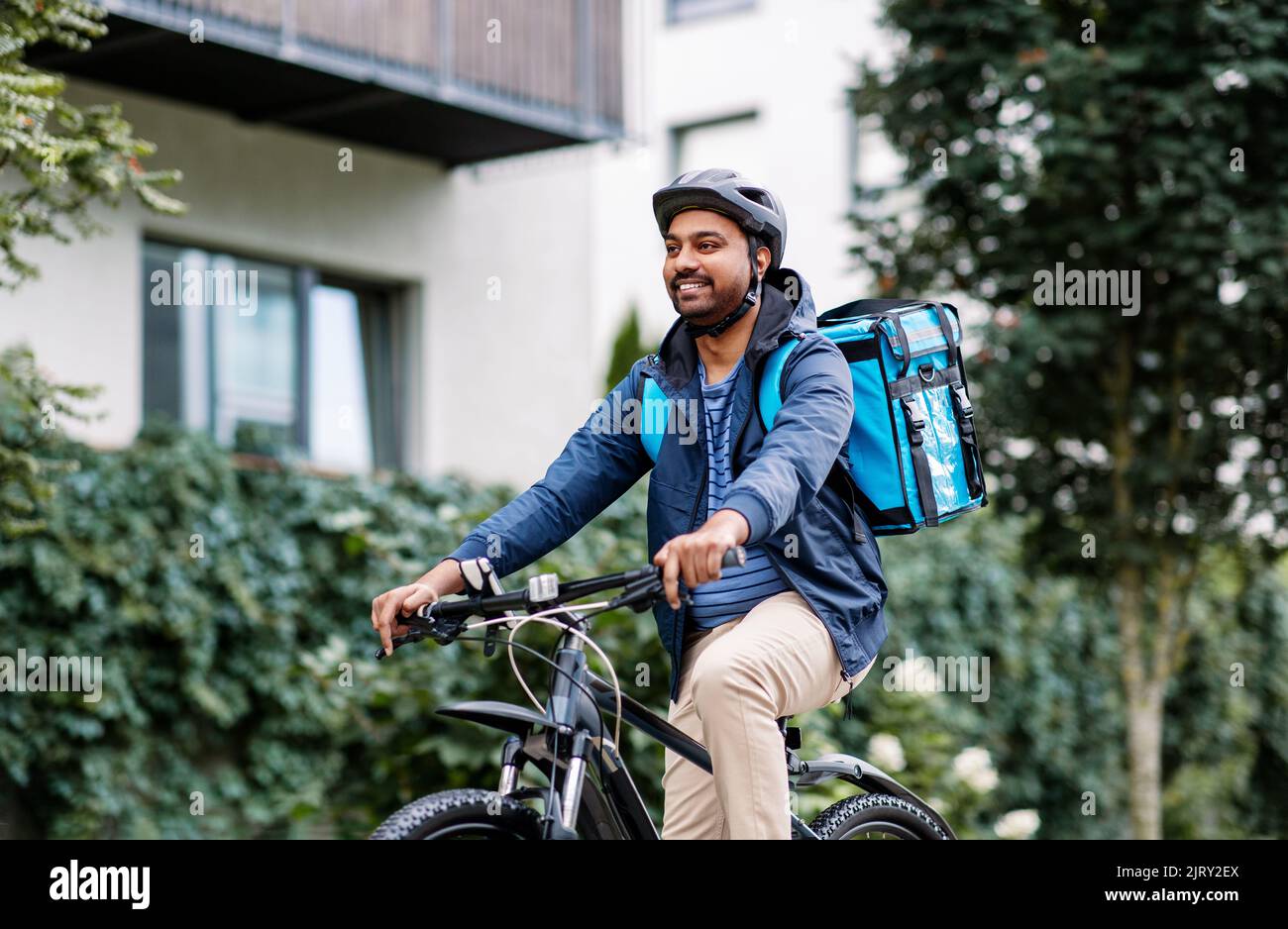 indian delivery man with bag riding bicycle Stock Photo