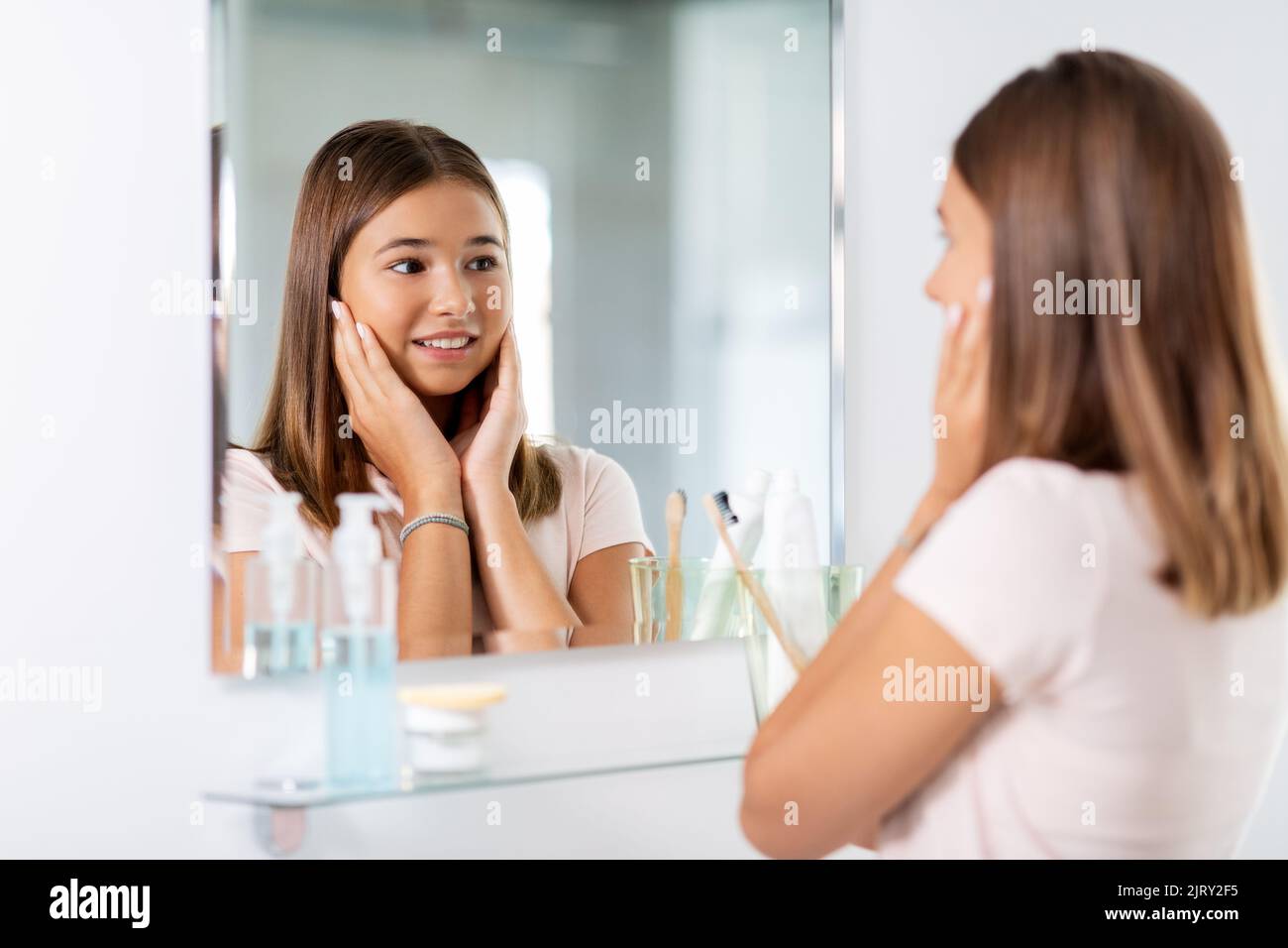 teenage girl looking in mirror at bathroom Stock Photo - Alamy
