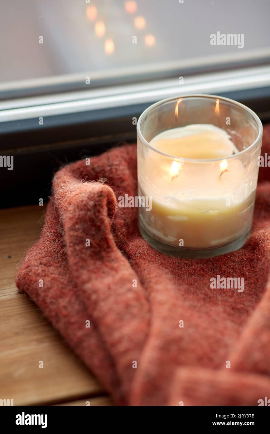 woolen sweater and candle burning on window sill Stock Photo Alamy
