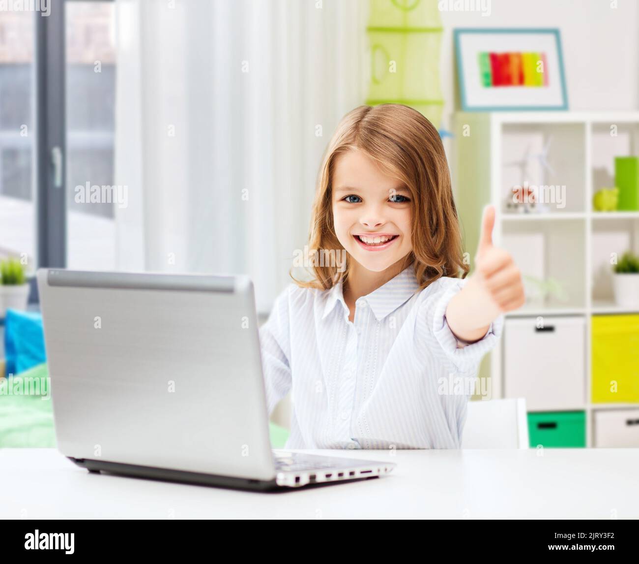 smiling student girl with laptop showing thumbs up Stock Photo - Alamy