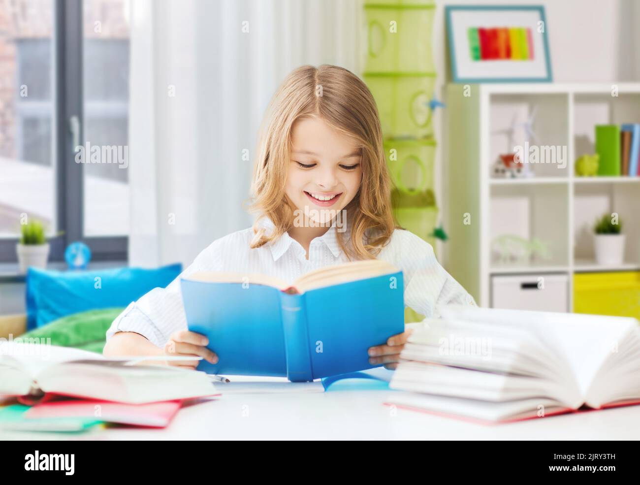 happy smiling student girl reading book at home Stock Photo - Alamy