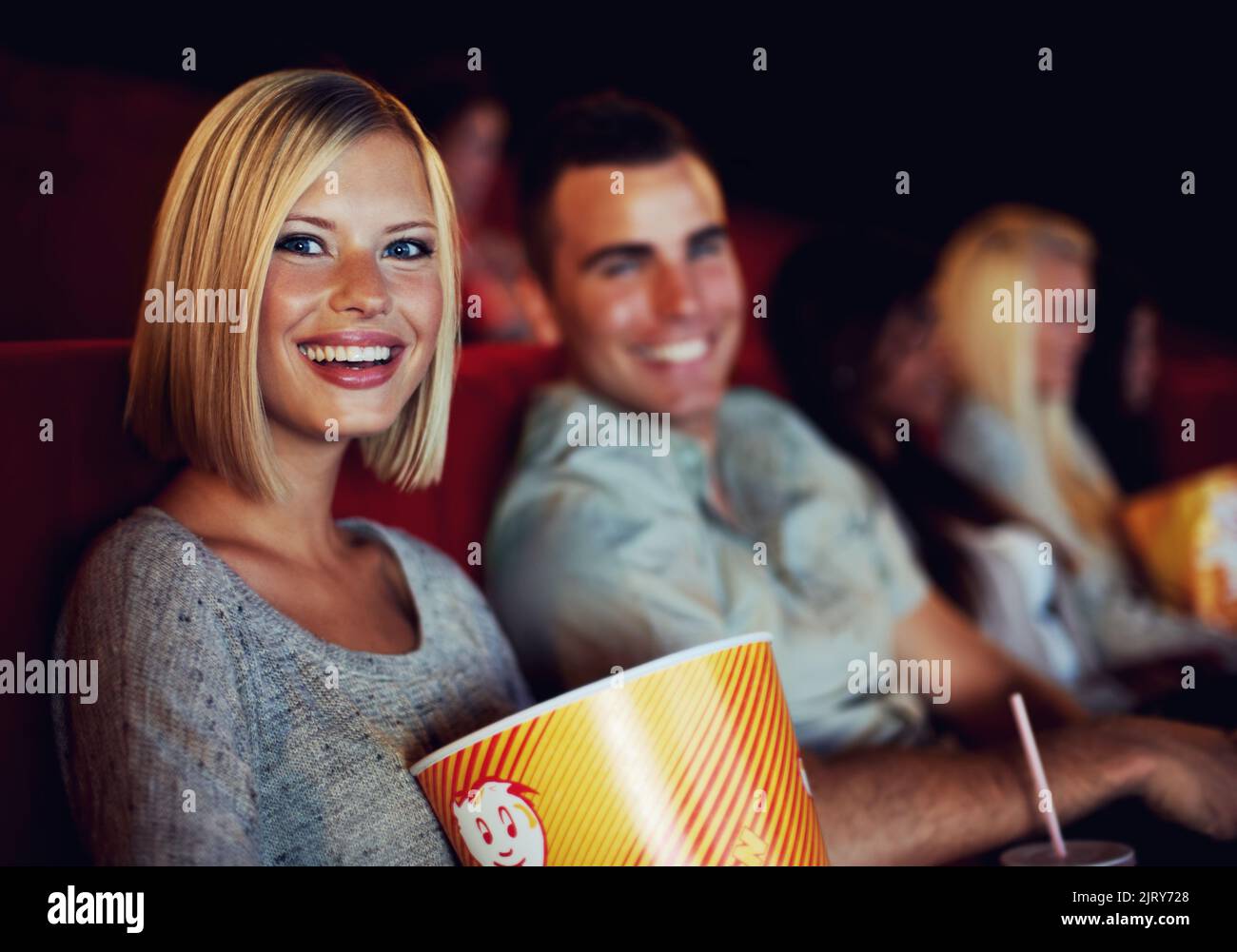 Movie, popcorn and smile with woman on a date with man at cinema interior or theater event. Happy, film or show screen with couple eating snacks and Stock Photo