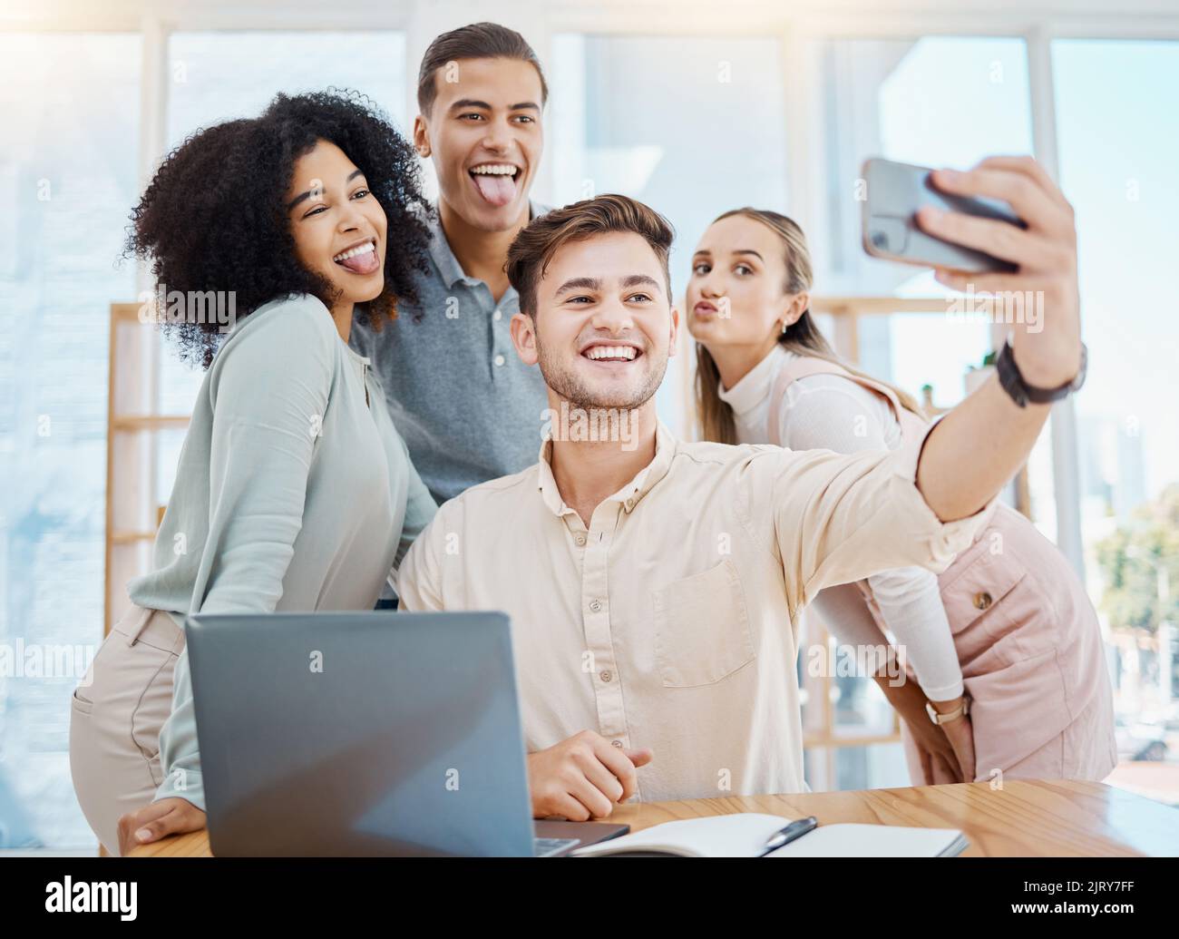 Office selfie with happy corporate colleagues having fun and being goof, silly face expressions while bonding. Young, diverse work friends relaxing on Stock Photo