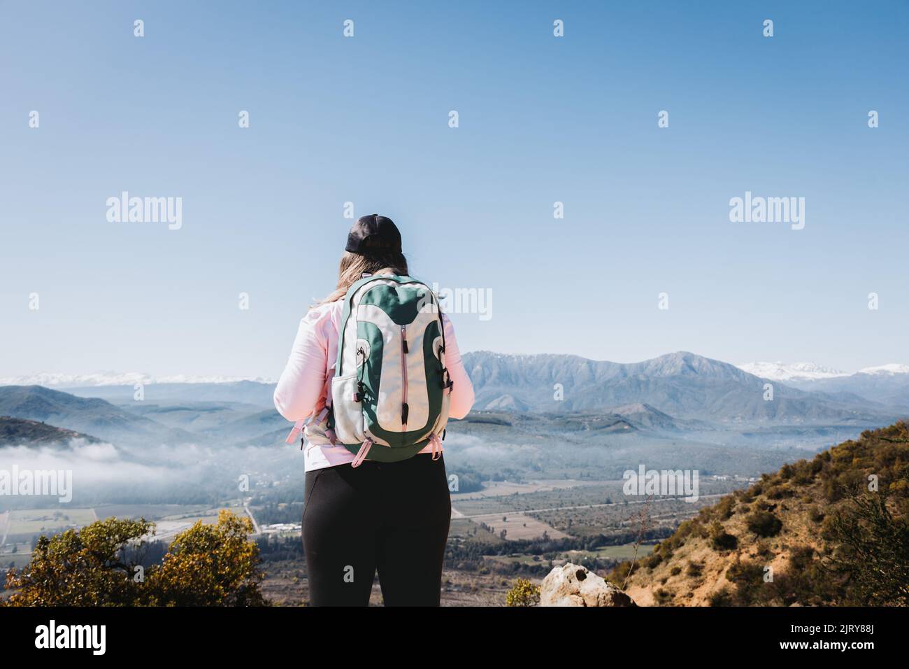 Rear view young latin plus size woman with backpack on, at the top of a hill  Stock Photo