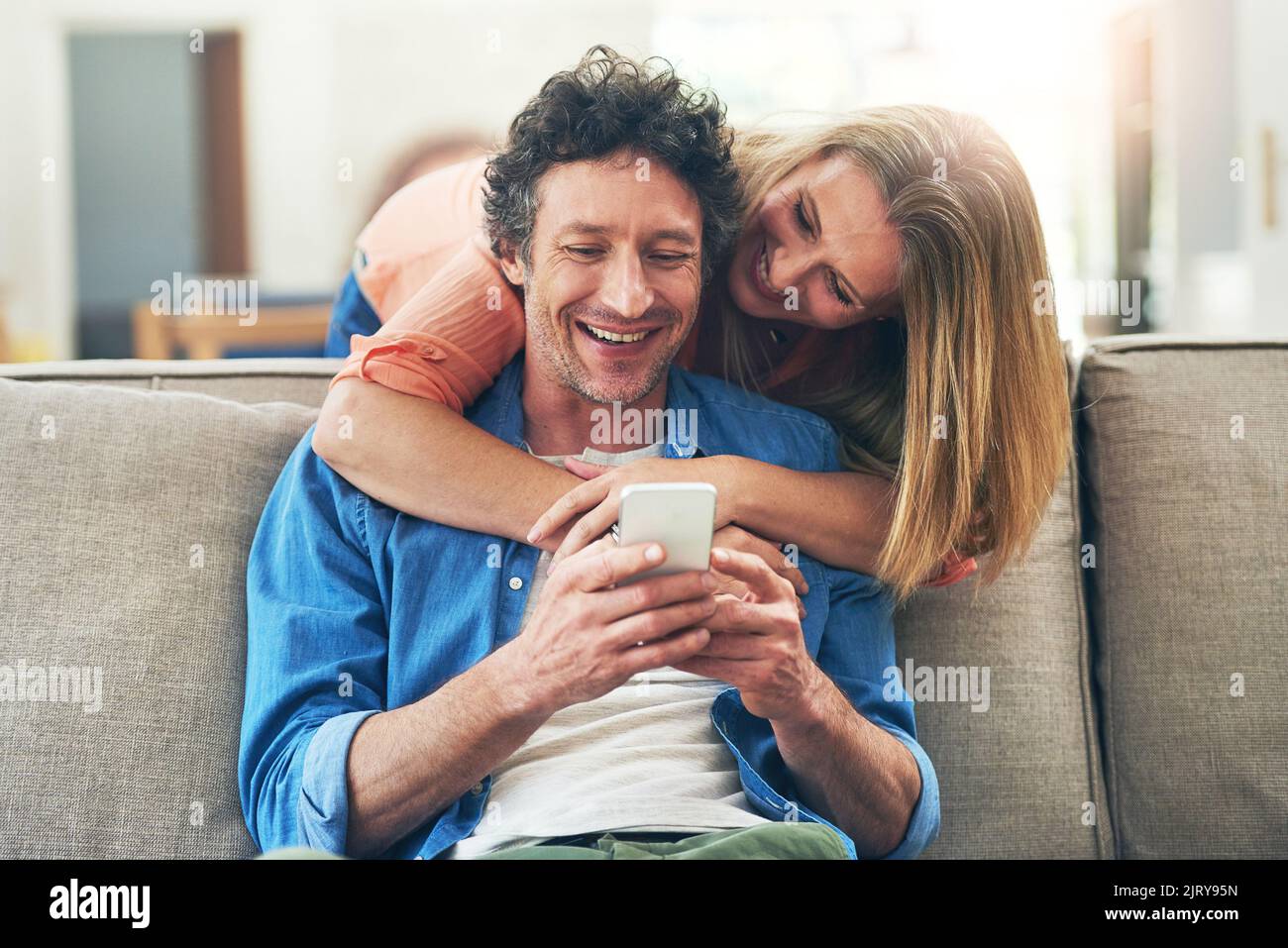 Guess who just texted. a happy mature couple using a mobile phone together at home. Stock Photo