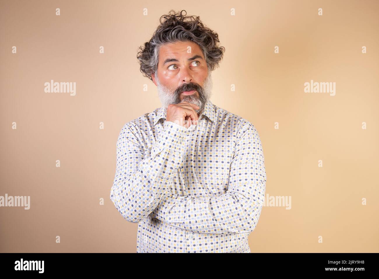 Middle age grey-haired man in casual clothes with hand on chin thinking about question, expression of penitence. doubt concept. Stock Photo