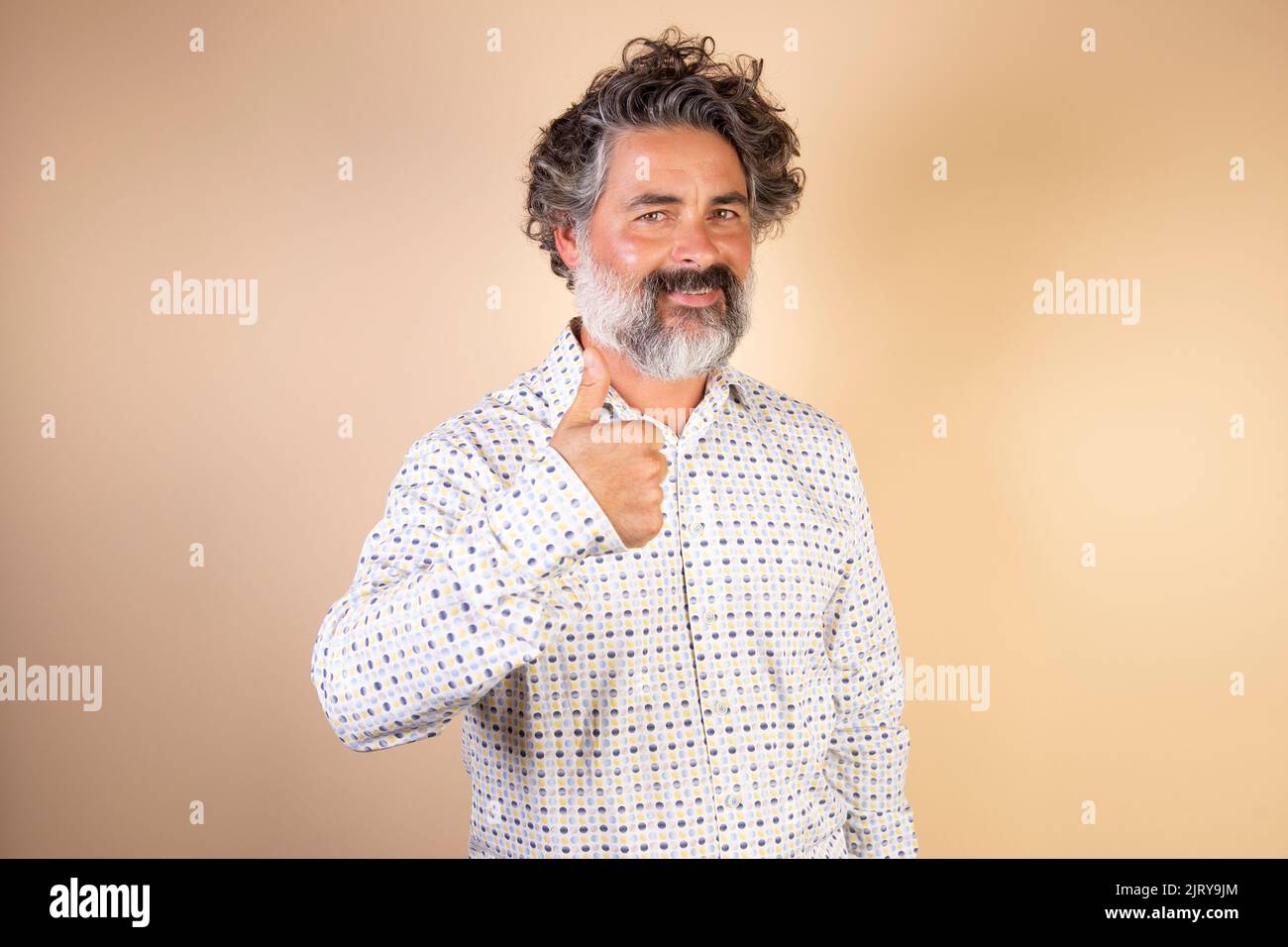 Middle age man with gray hair and beard wearing casual clothes making happy thumbs up gesture with hand. approving expression looking at camera showin Stock Photo