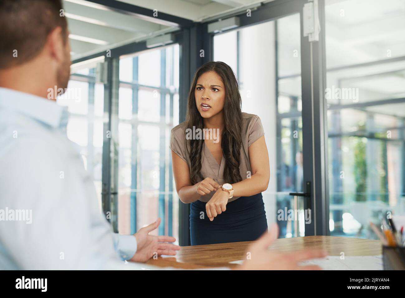 Do you even know what time it is. an angry businesswoman scolding her colleague for being late in the office. Stock Photo