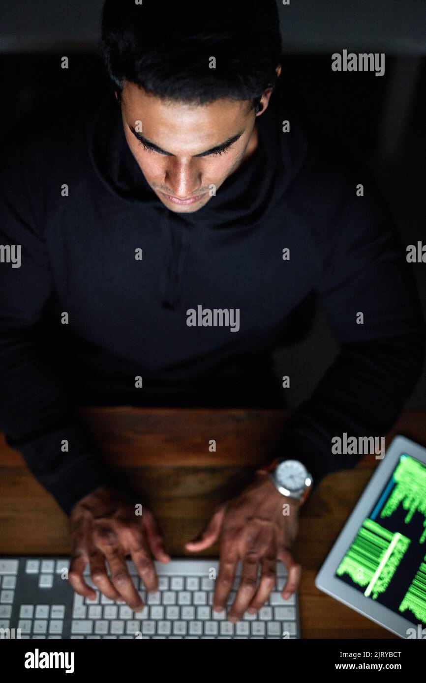 Testing out his latest code. High angle shot of a young hacker cracking ...