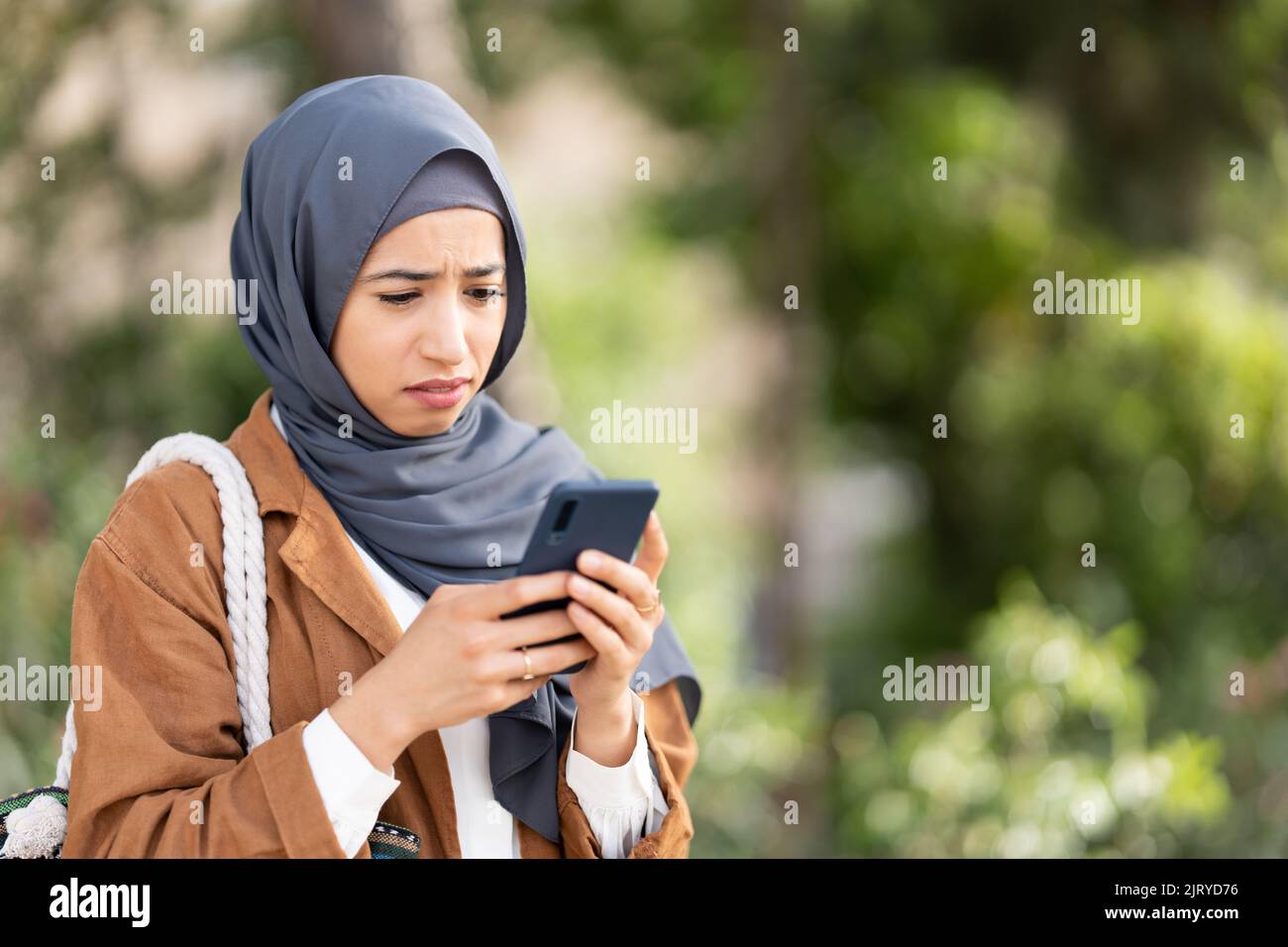 Muslim woman using mobile with a sad expression of disgust Stock Photo