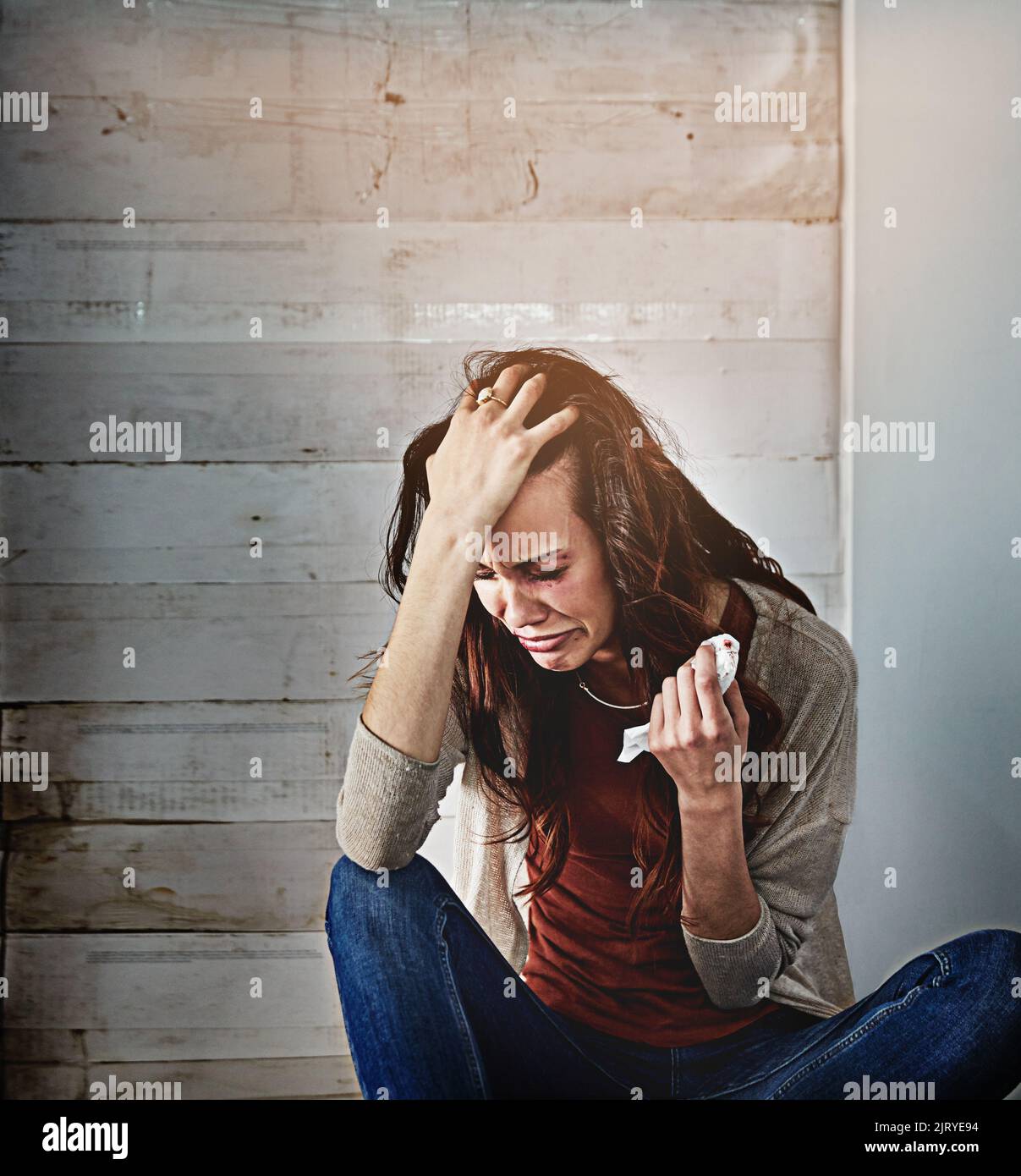 She feels helpless. a beaten and bruised young woman crying. Stock Photo