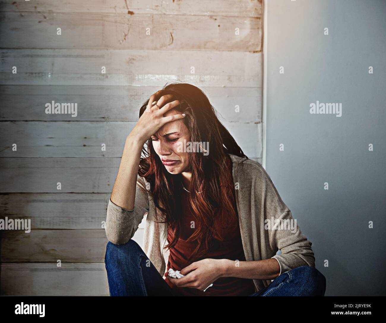 All she can do is cry. a beaten and bruised young woman crying. Stock Photo