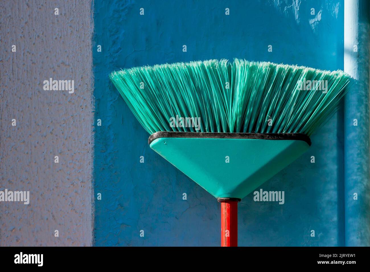 Green broom leaning against a blue house wall, Italy Stock Photo Alamy