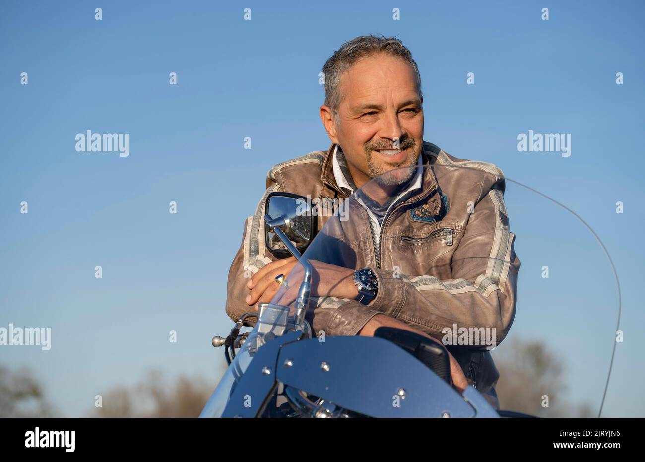Middle-aged man with leather jacket standing by motorbike, Karlsruhe, Germany Stock Photo