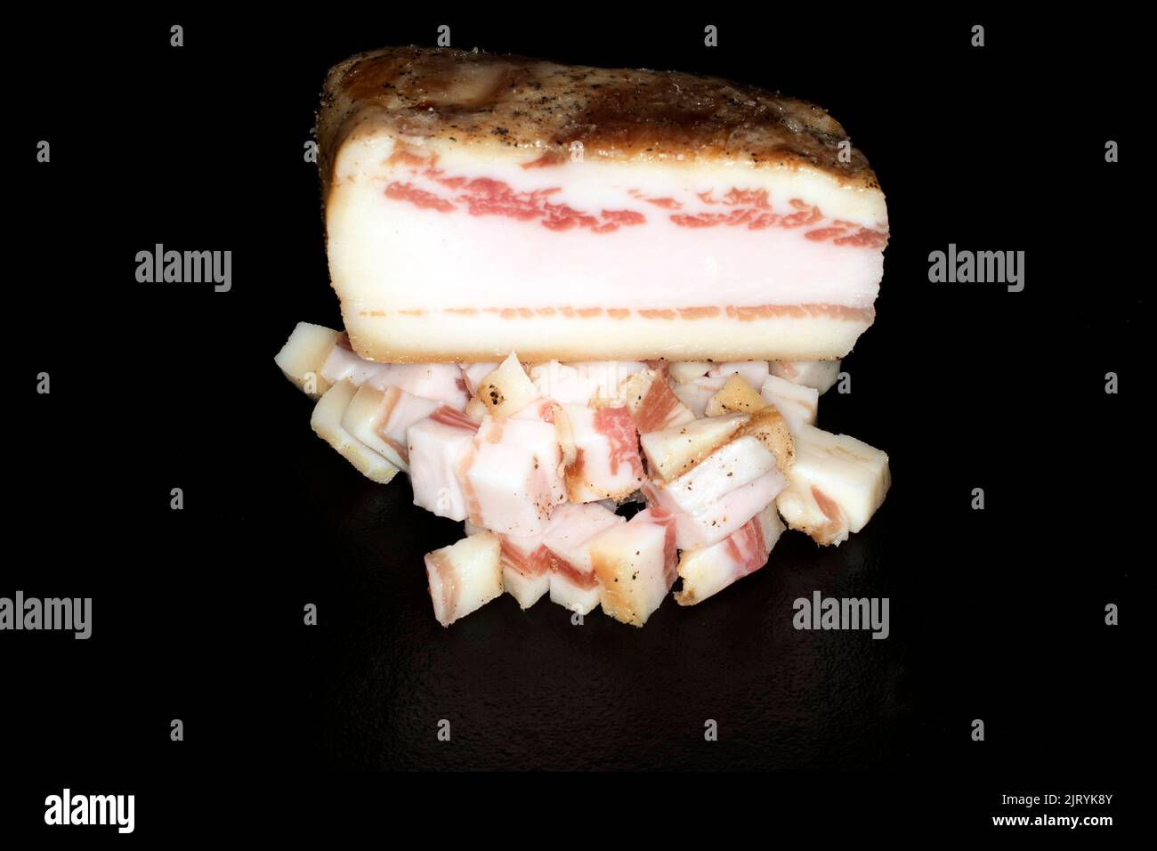 Pancetta whole and diced, food photography with black background Stock