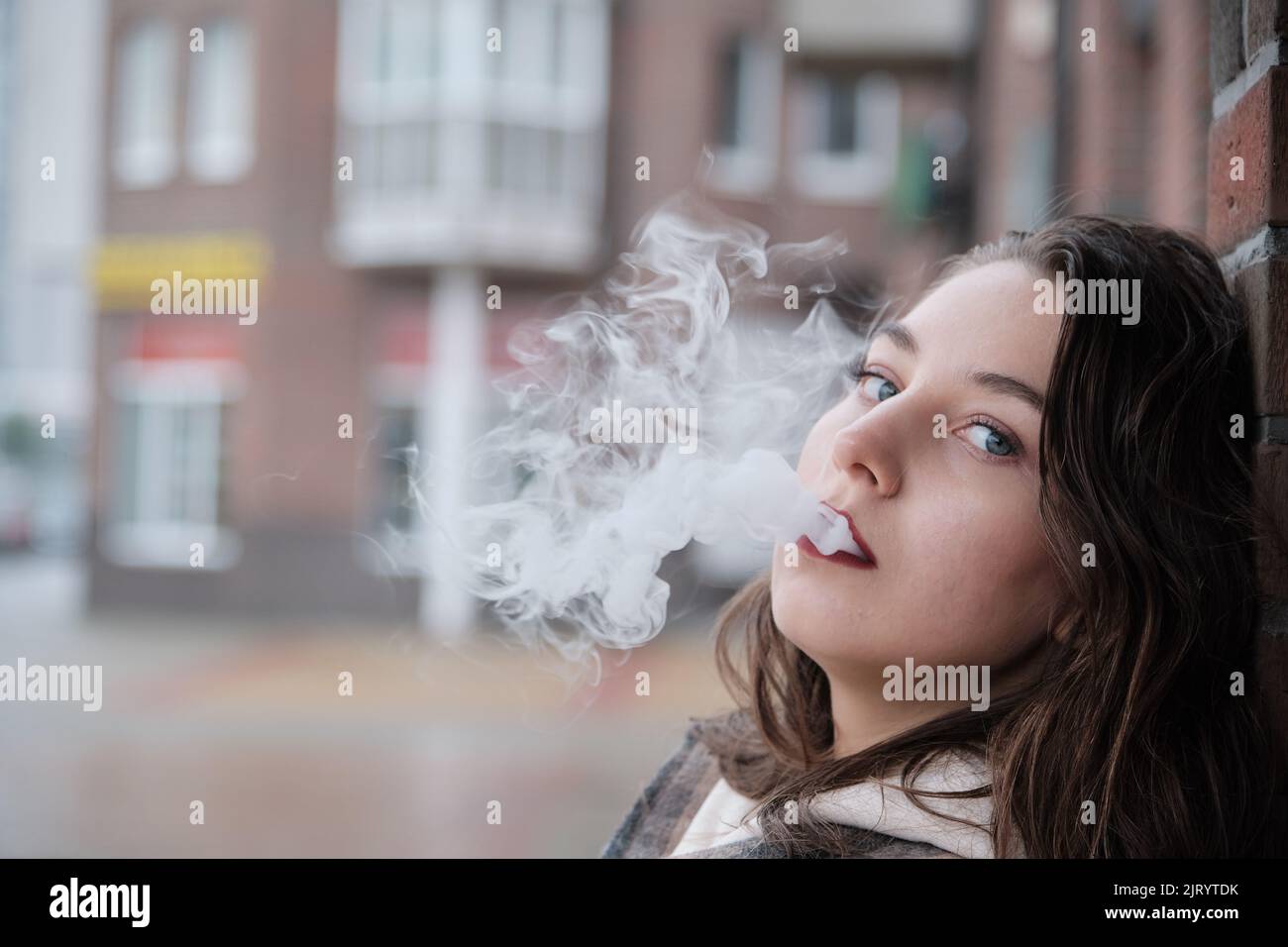 young woman on city street exhale smoke closeup portrait Stock Photo