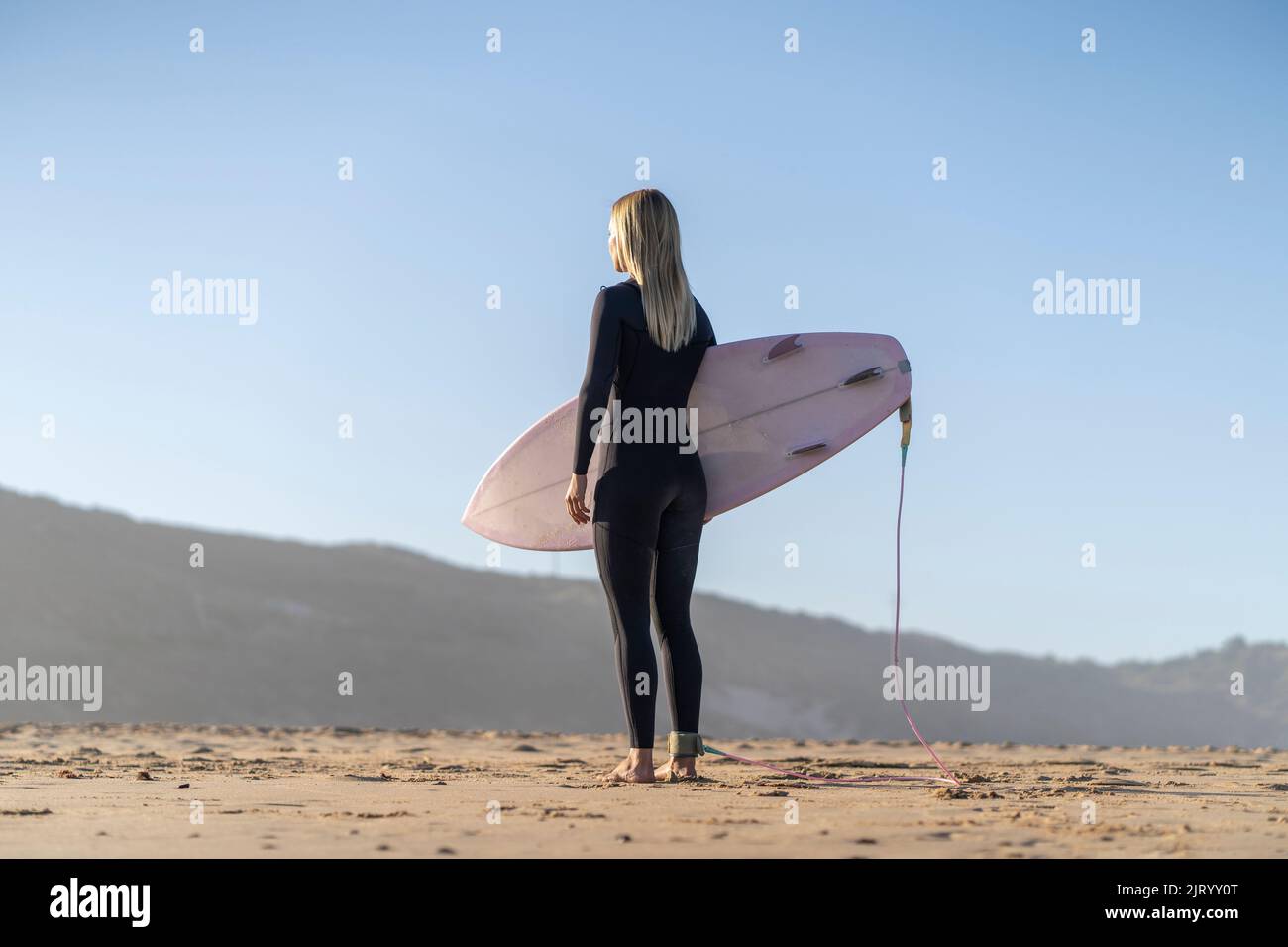 Surfer girl at the beach standing with her surfboard in the morning. Female surfer Stock Photo