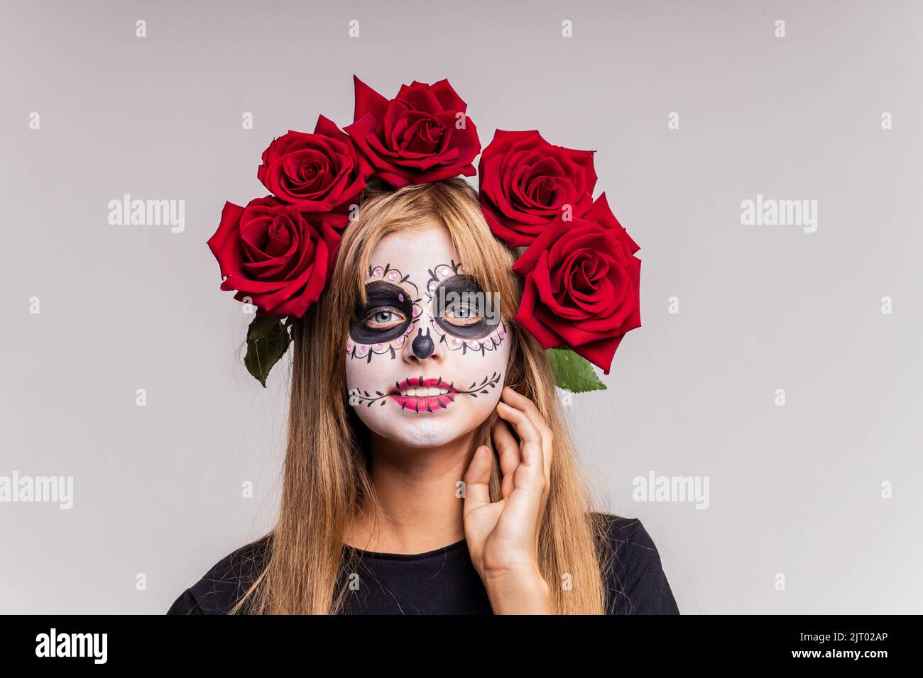 teenager girl with cool skull makeup with roses on head looking at camera in studio Stock Photo