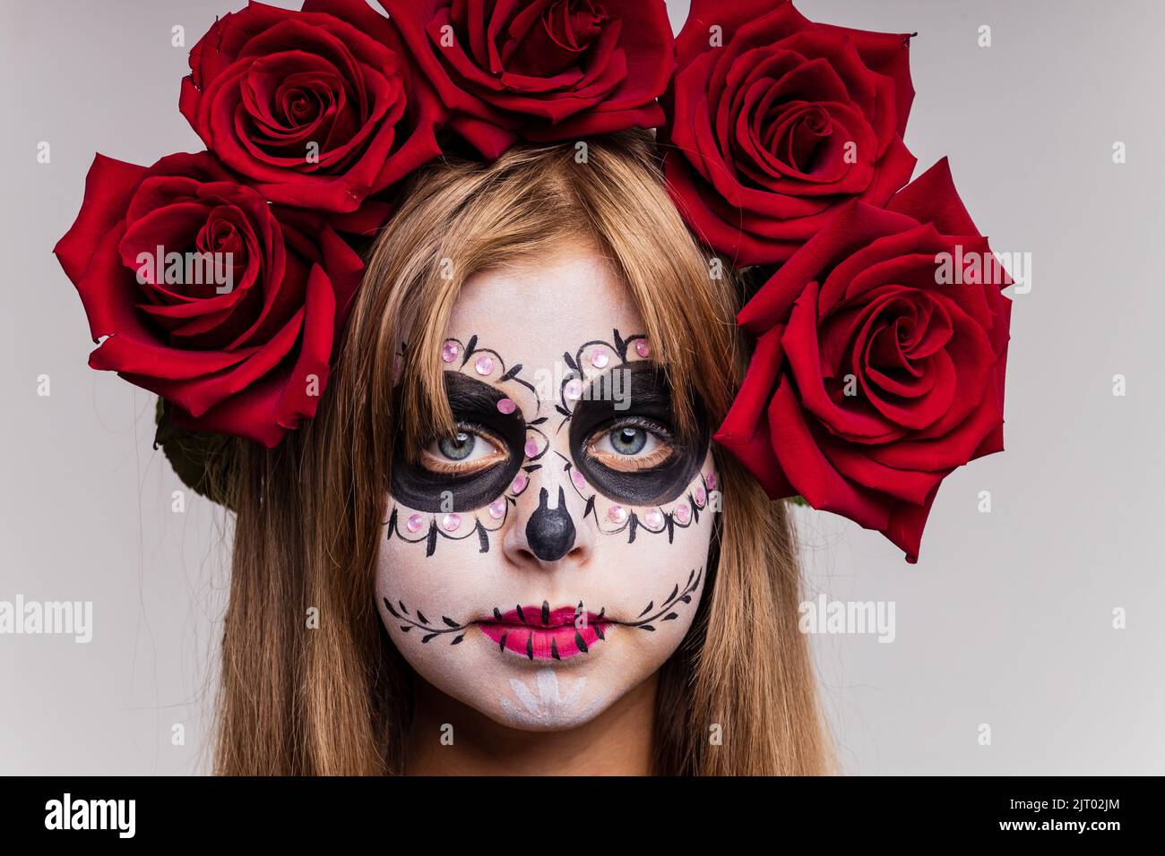 teenager girl with cool skull makeup with roses on head looking at camera in studio Stock Photo