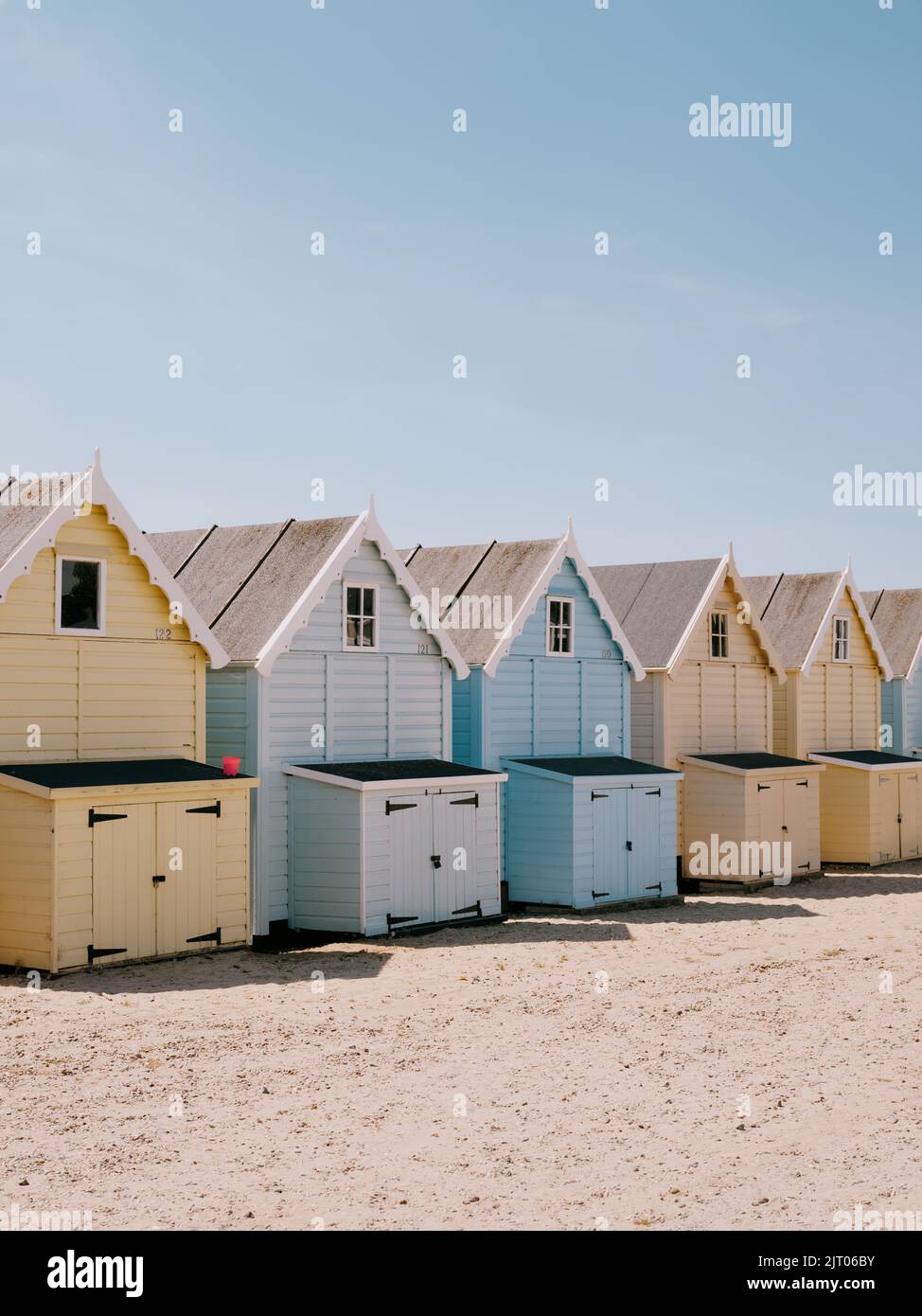 The pastel painted summer beach huts and blue sky on the beach in West Mersea, Mersea Island, Essex, England UK Stock Photo