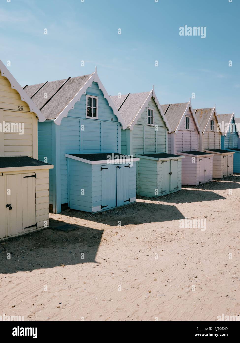 The pastel painted summer beach huts and blue sky on the beach in West Mersea, Mersea Island, Essex, England UK Stock Photo