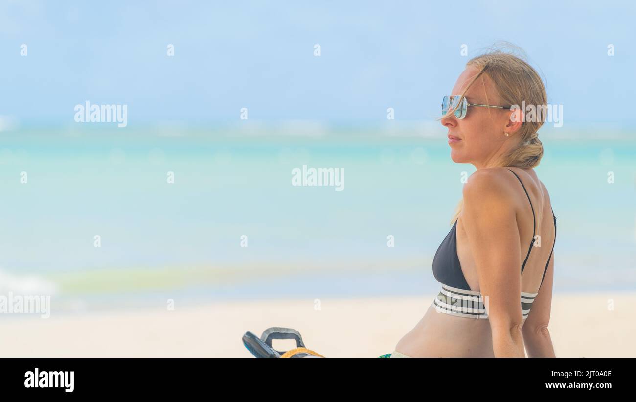 blonde woman relaxing on tropical beach with sunglasses in bikini Stock Photo